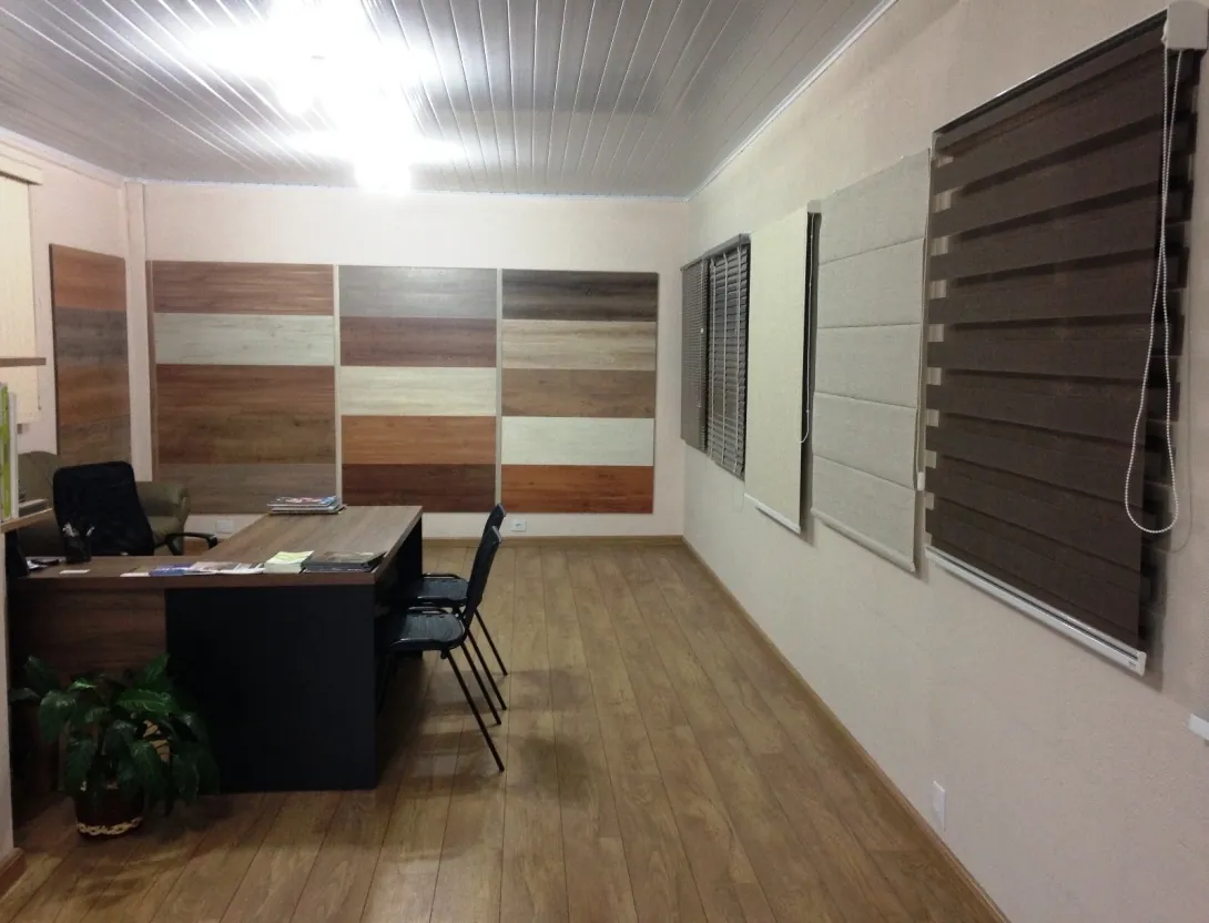 Showroom da Realize Pisos com mesa de atendimento, painel de amostras de piso e persianas expostas